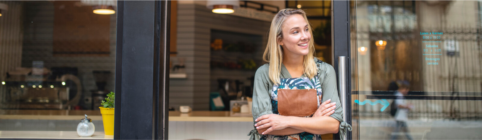 Woman wearing apron and casually leaning on business front