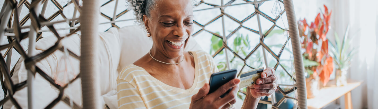 woman in chair using credit card on mobile phone