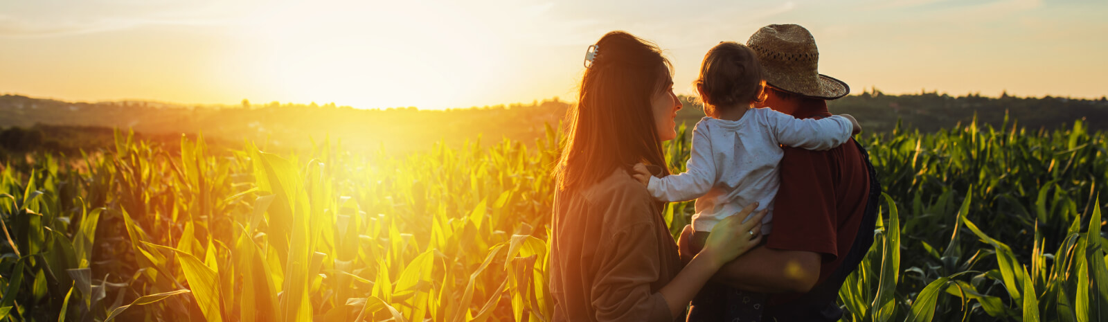 Young family standing in a crop field