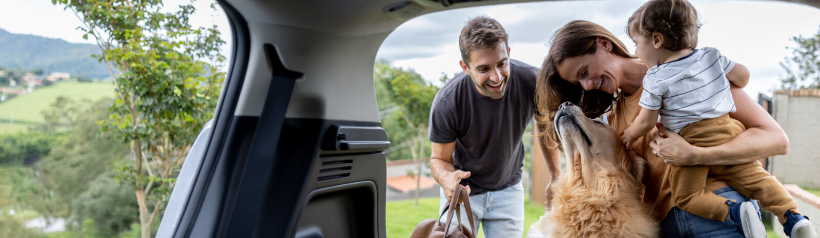 Young family and dog taking items out of the back of a SUV